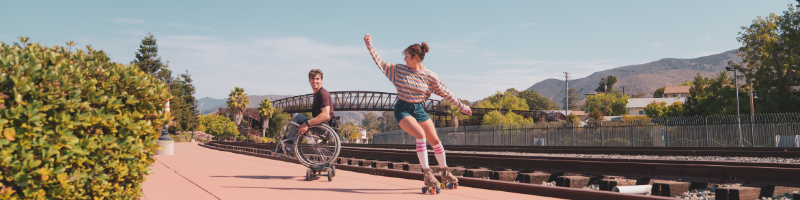 A young man in a wheelchair and a young woman on roller skates at Railroad Square