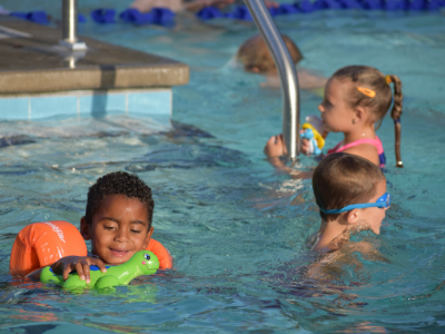 Three children play with toys in the pool