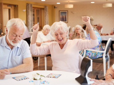 A mature man and woman are sitting at a table playing bingo. 