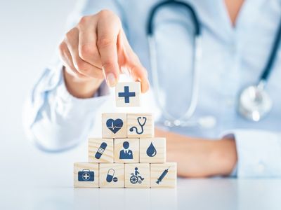 A person wearing a stethoscope assembles health-related building blocks.