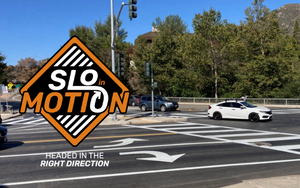 A car drivers through a freshly painted intersection; SLO in Motion logo with "Headed in the Right Direction" tagline