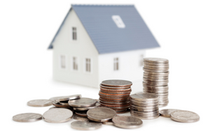 A picture of stacks of coins and loose coins in the foreground, and a small house replica in the background