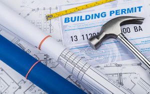 A picture of building permits with rolled up plans and a hammer