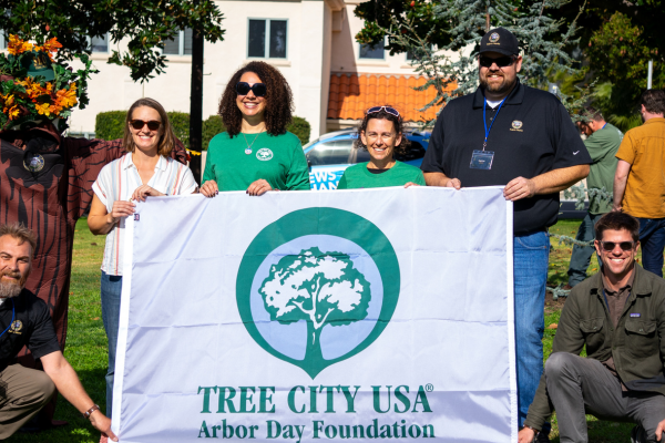 A picture of SLO's Urban Forester, council members, and Public Works Deputy Director, holding up a Tree City USA flag at Arbor Day 2022