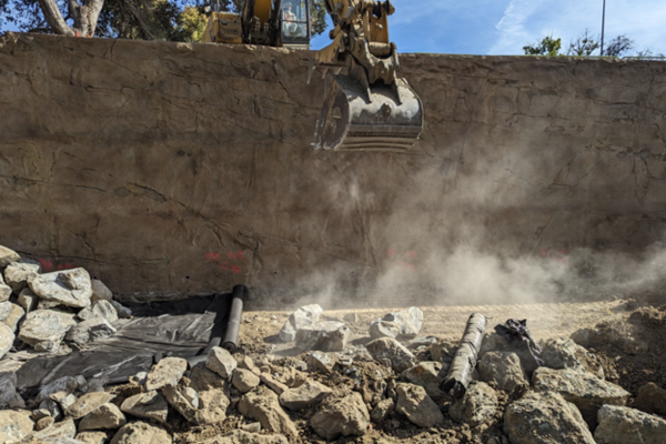 A bulldozer drops boulders at the base of the new creek wall along San Luis Drive.