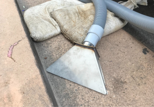 Vacuum setup in front of sandbag in dry gutter, ready to remove washwater