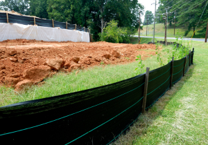 Silt fence with green grass on one side and construction on the other