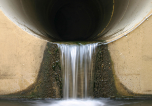 Water flowing out of large circular concrete stormwater outfall