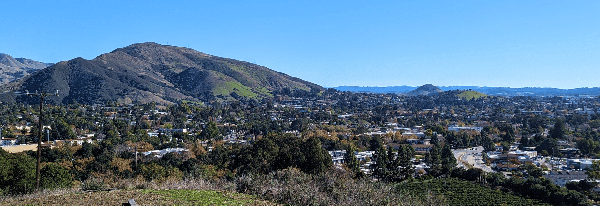 Blue sky and green hills behind San Luis High School in the background,