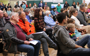 A crowd is seated at a Community Forum. 